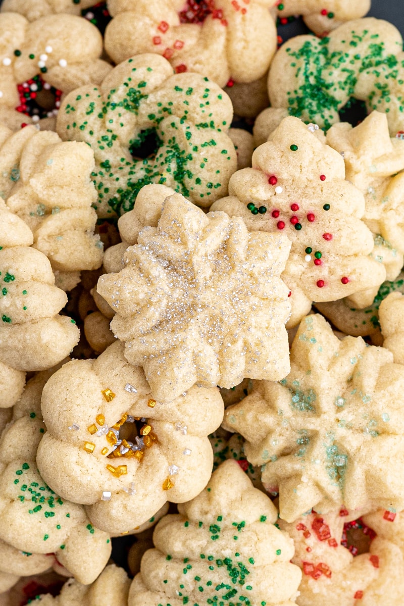overhead view of a big pile of spritz cookies decorated with red, green, gold, and silver sprinkles