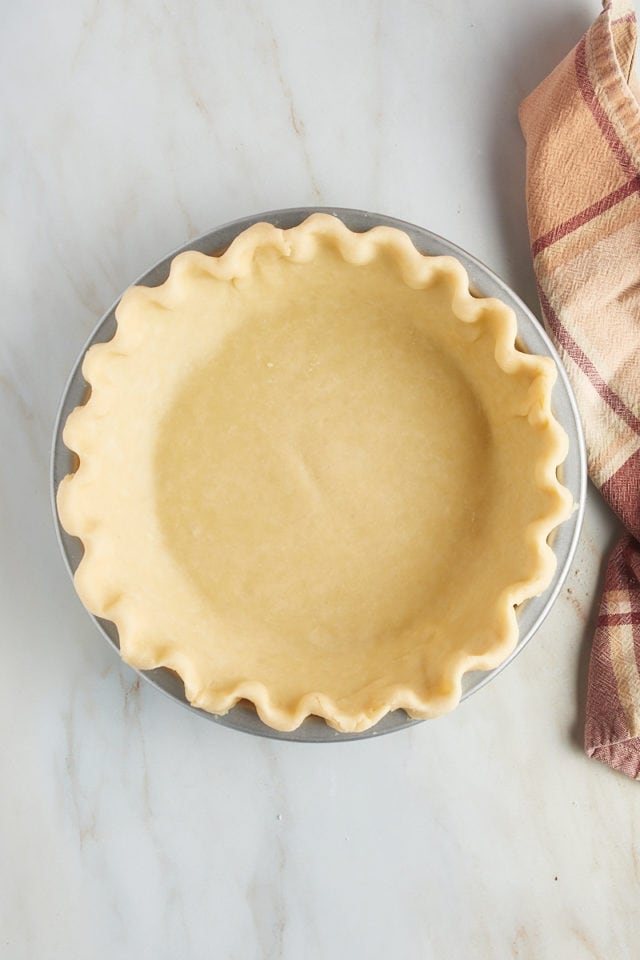 overhead view of rolled and crimped pie crust in a pie plate