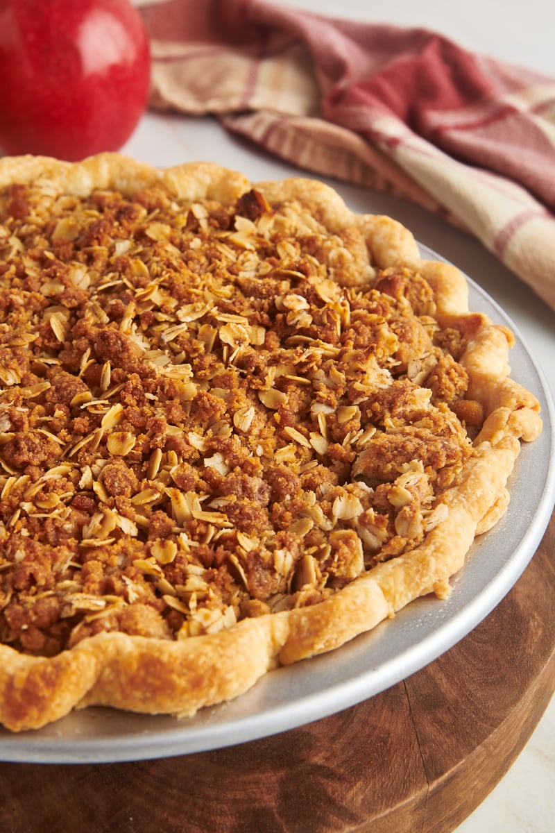 apple crumb pie in a metal pie pan on a wooden board