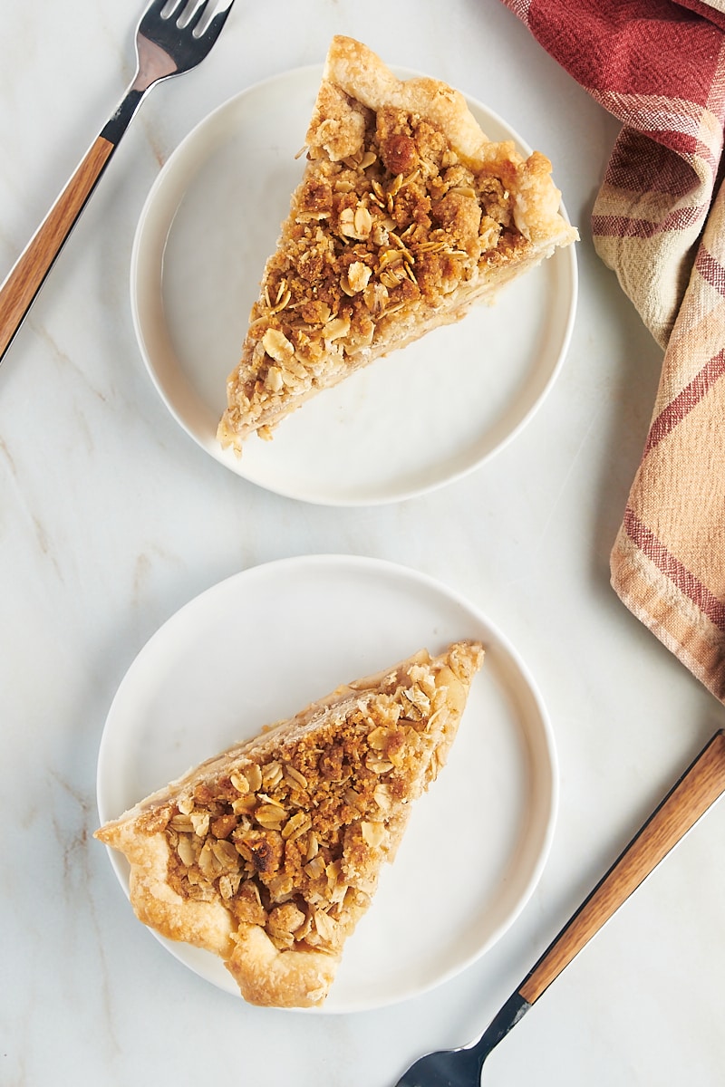 overhead view of two slices of apple crumb pie on white plates