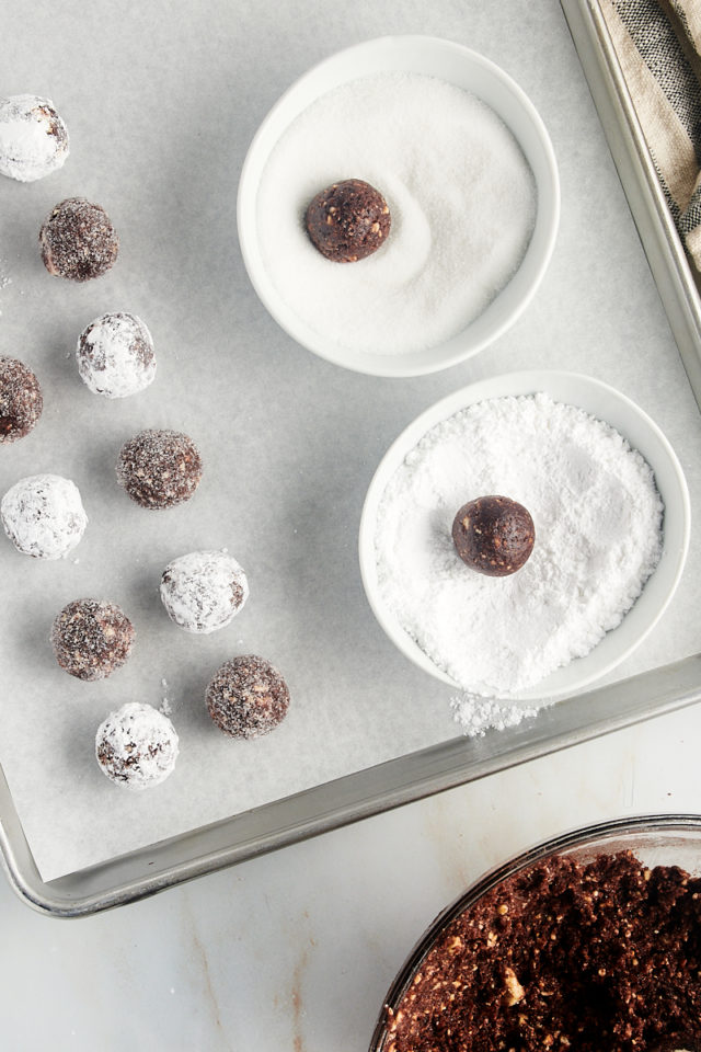overhead view of bourbon balls being rolled in granulated sugar and powdered sugar