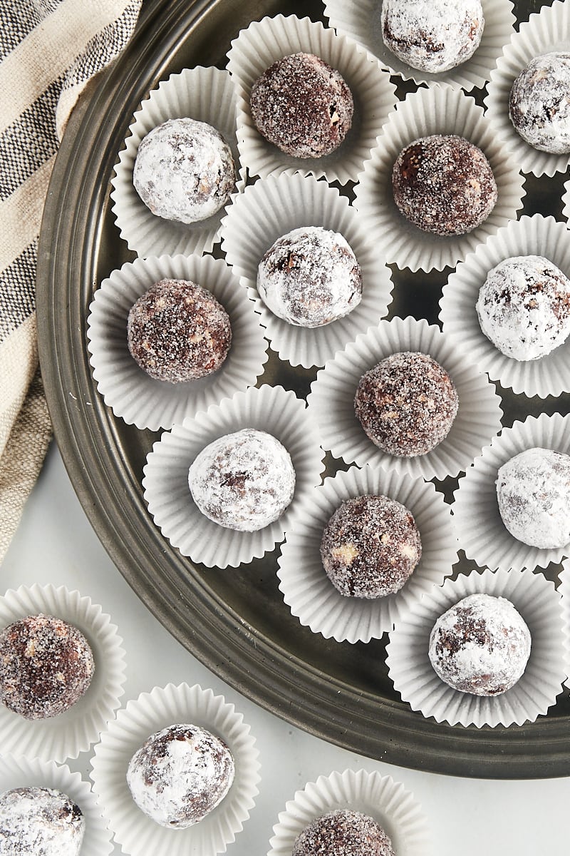 overhead view of bourbon balls in white mini muffin cups on a pewter tray