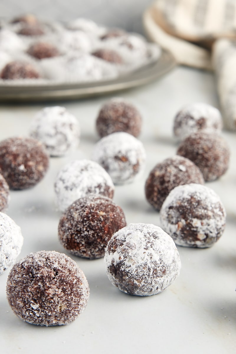 bourbon balls on a marble countertop with more on a pewter tray in the background