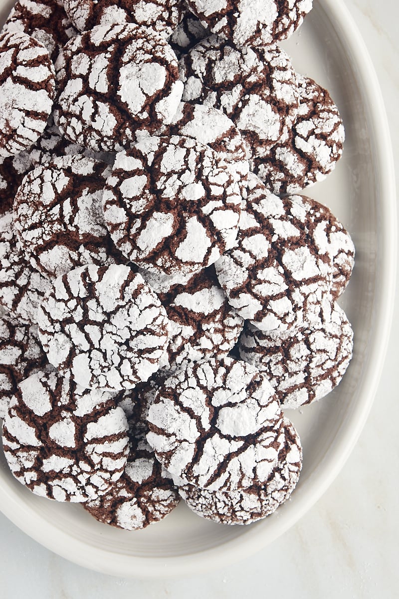 Overhead view of chocolate crinkle cookies on a white serving tray.