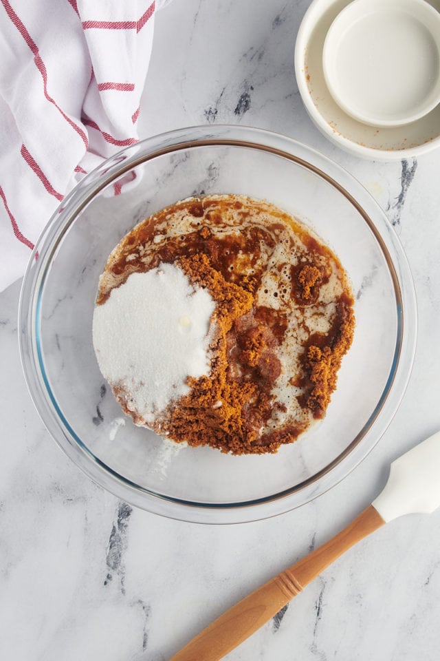 overhead view of Biscoff cookie crumbs, sugar, and melted butter in a glass mixing bowl