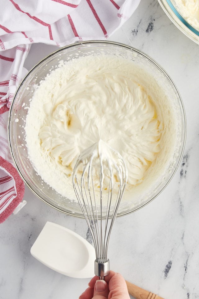 overhead view of heavy cream whipped to stiff peaks in a glass mixing bowl
