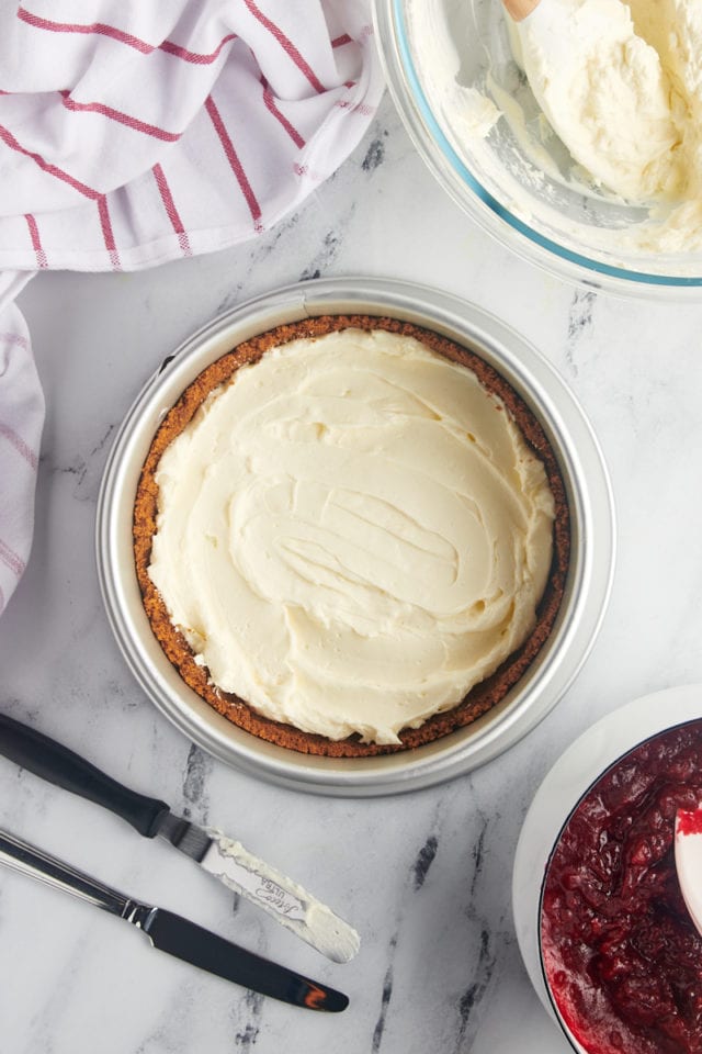 overhead view of half of the cheesecake filling spread in a Biscoff crust for no-bake cranberry cheesecake