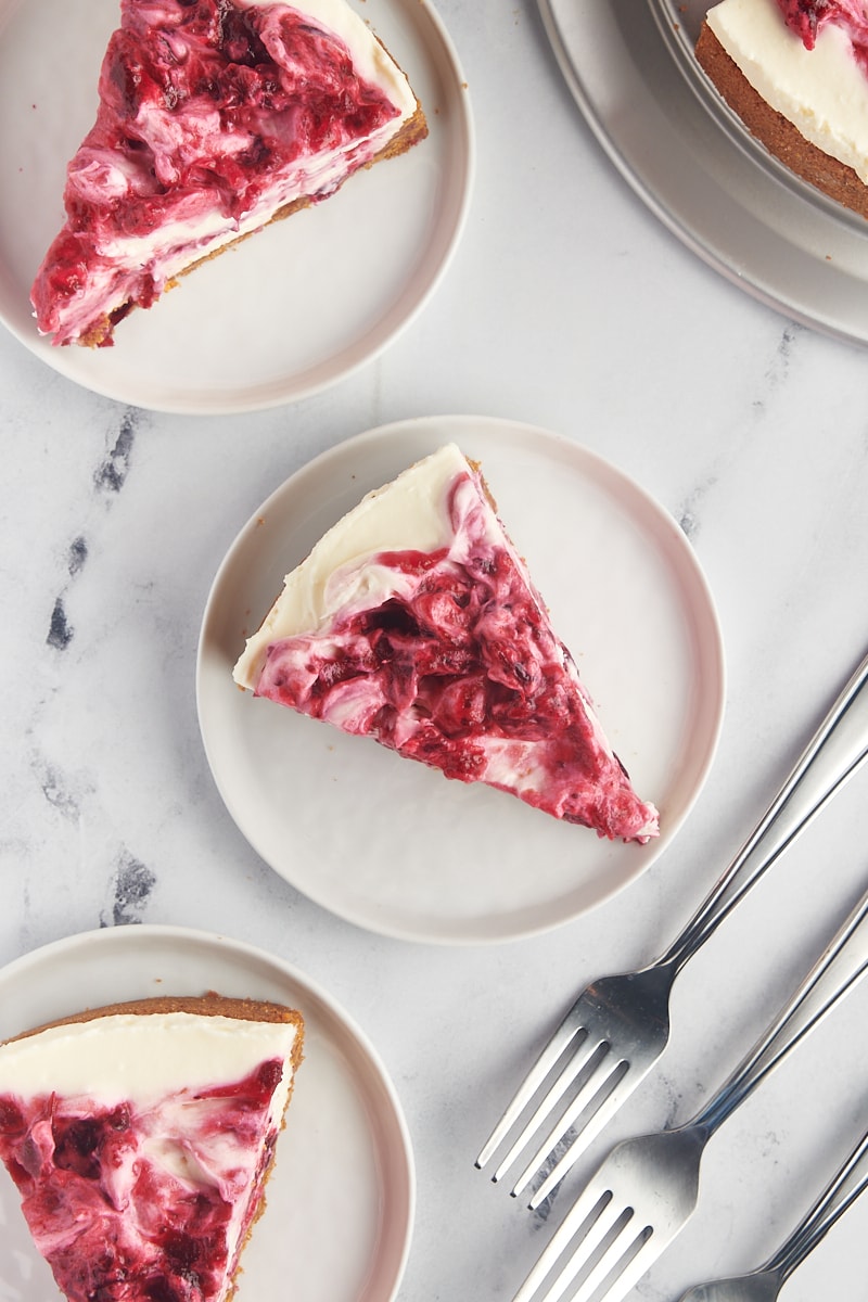 overhead view of three slices of no-bake cranberry cheesecake on white plates