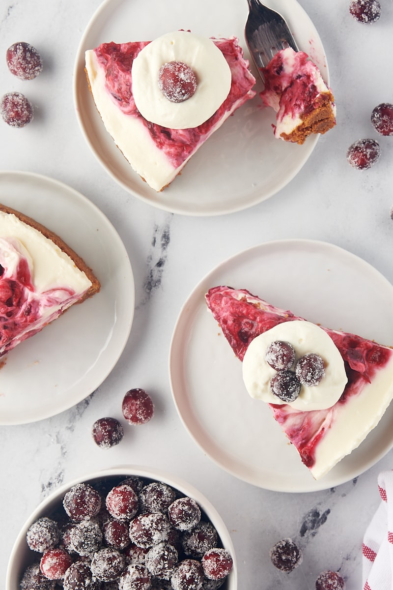 overhead view of three slices of no-bake cranberry cheesecake topped with whipped cream and sugared cranberries