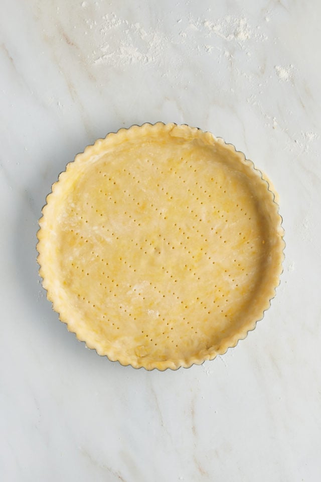 Overhead view of pastry crust in tart pan with fork pricks