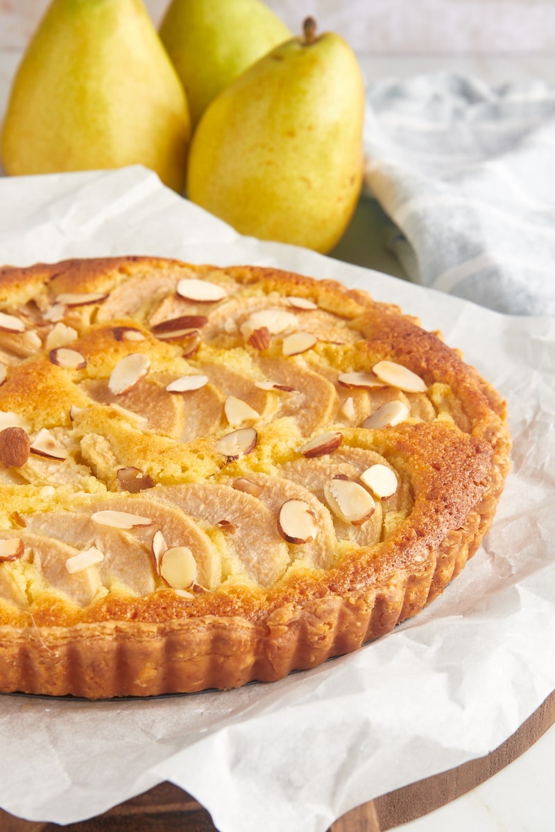 Whole pear frangipane tart on parchment-lined board