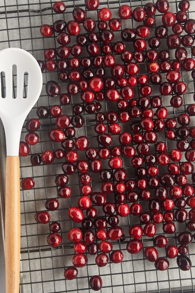 overhead view of syrup-coated cranberries drying on a wire rack