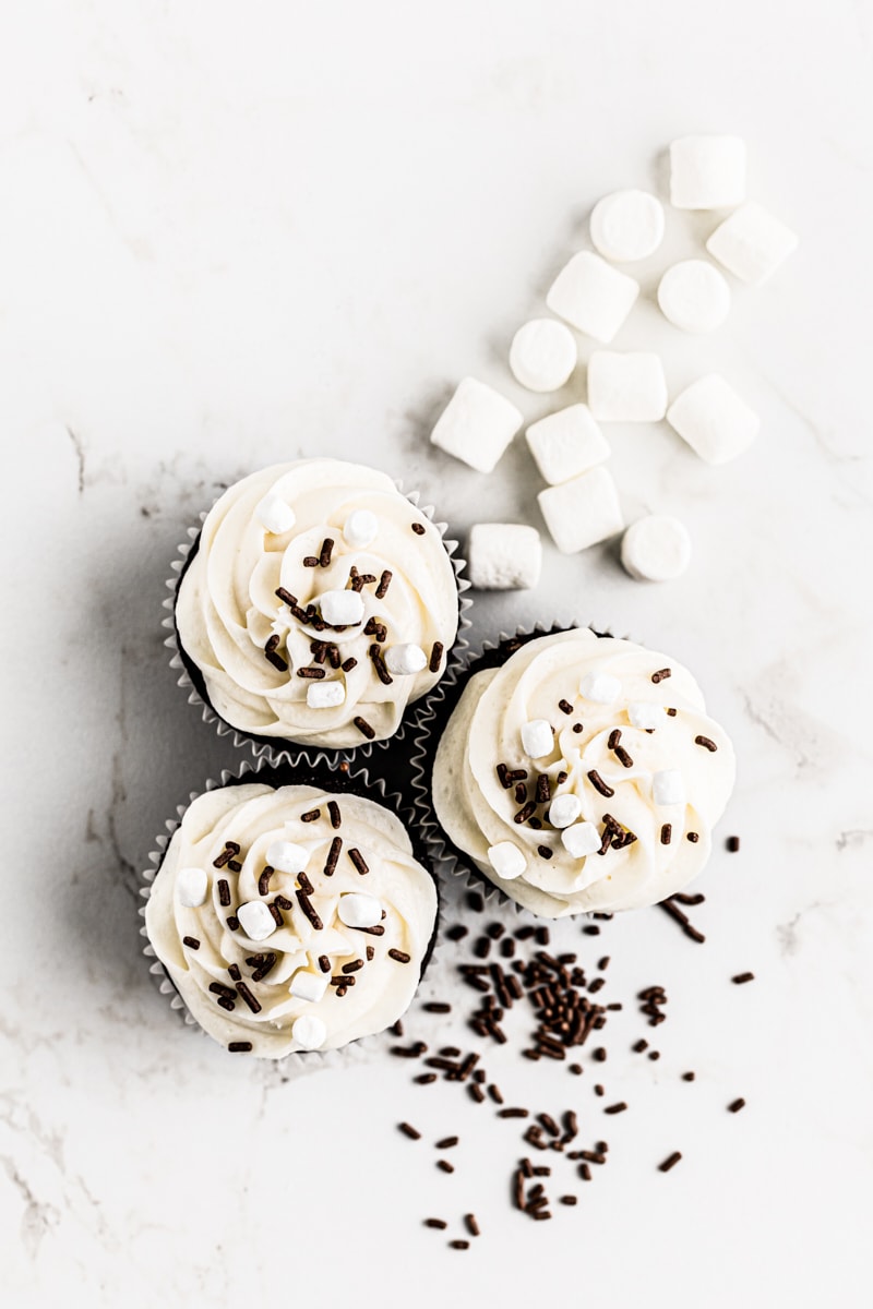 overhead view of hot chocolate cupcakes topped with chocolate sprinkles and marshmallow bits