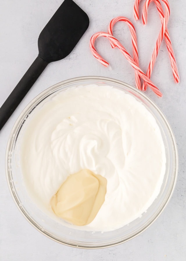 overhead view of sweetened condensed milk and peppermint extract added to whipped cream