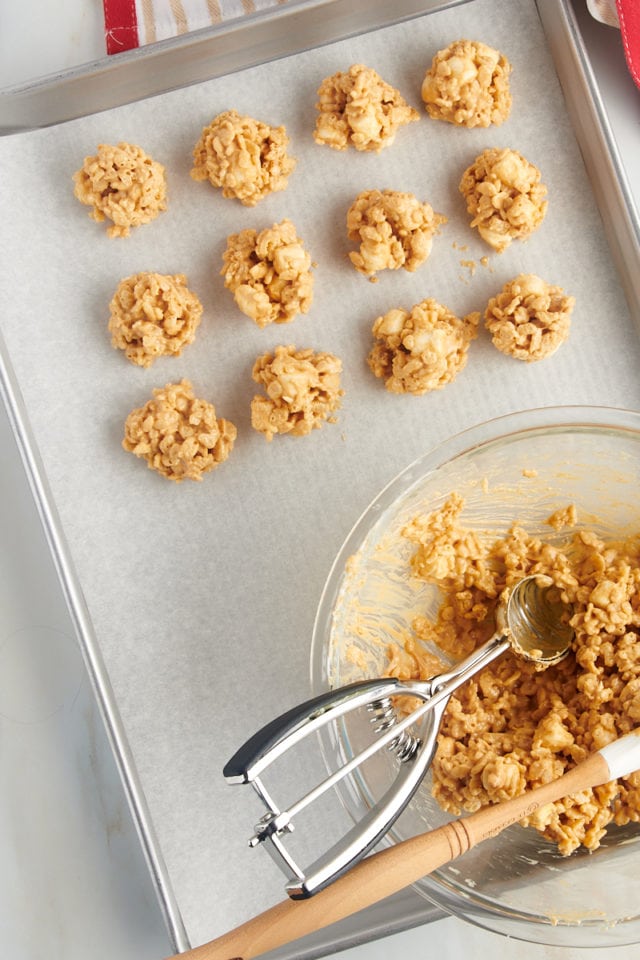 overhead view of avalanche cookies being scooped onto a parchment-lined baking sheet