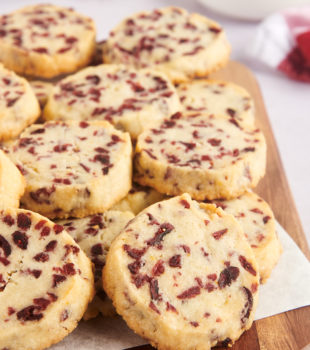 Pile of cranberry orange shortbread cookies on cutting board