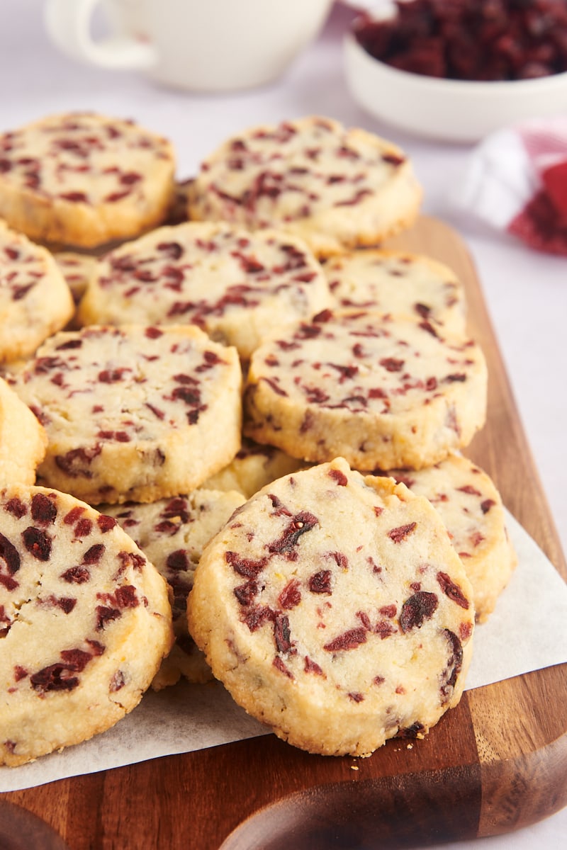 Pile of cranberry orange shortbread cookies on cutting board