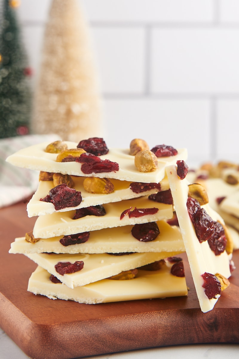 several pieces of cranberry pistachio bark stacked on a wooden cutting board