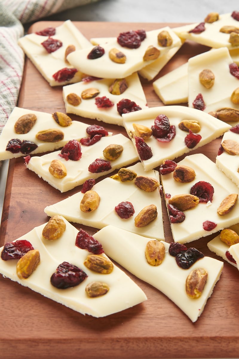 cranberry pistachio bark scattered on a wooden cutting board