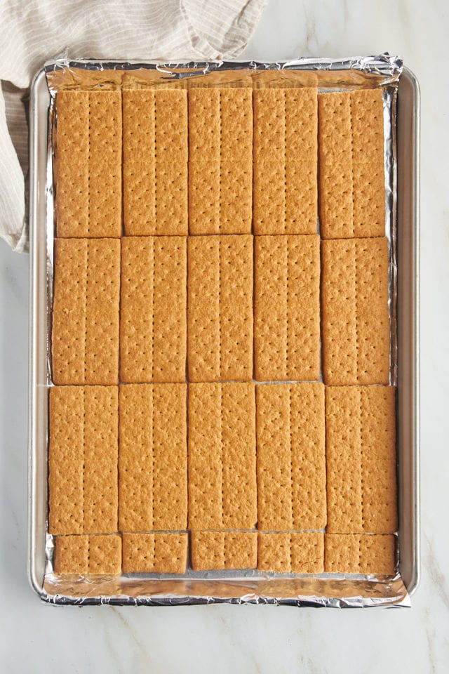 overhead view of a layer of graham crackers filling a foil-lined half sheet pan