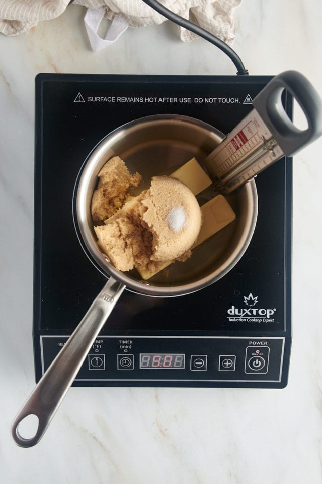 overhead view of butter, brown sugar, and salt in a saucepan with a candy thermometer attached