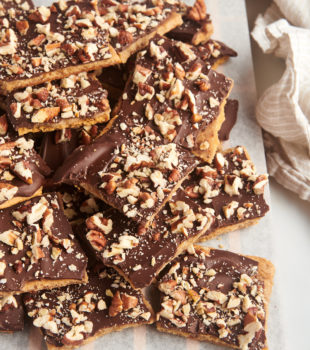 graham cracker toffee piled on a parchment-lined wooden board