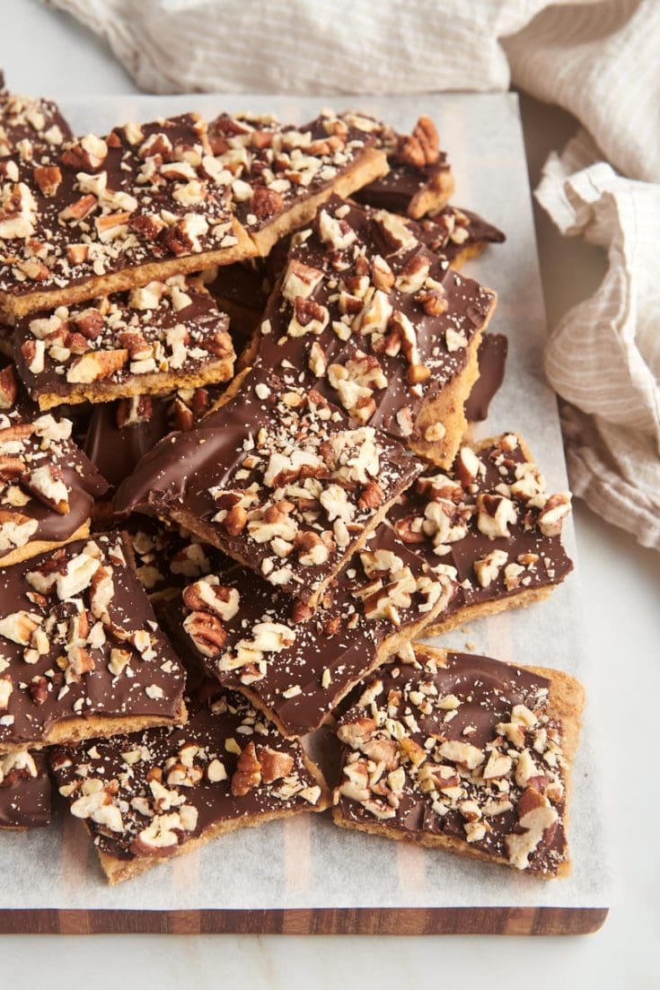 graham cracker toffee piled on a parchment-lined wooden board