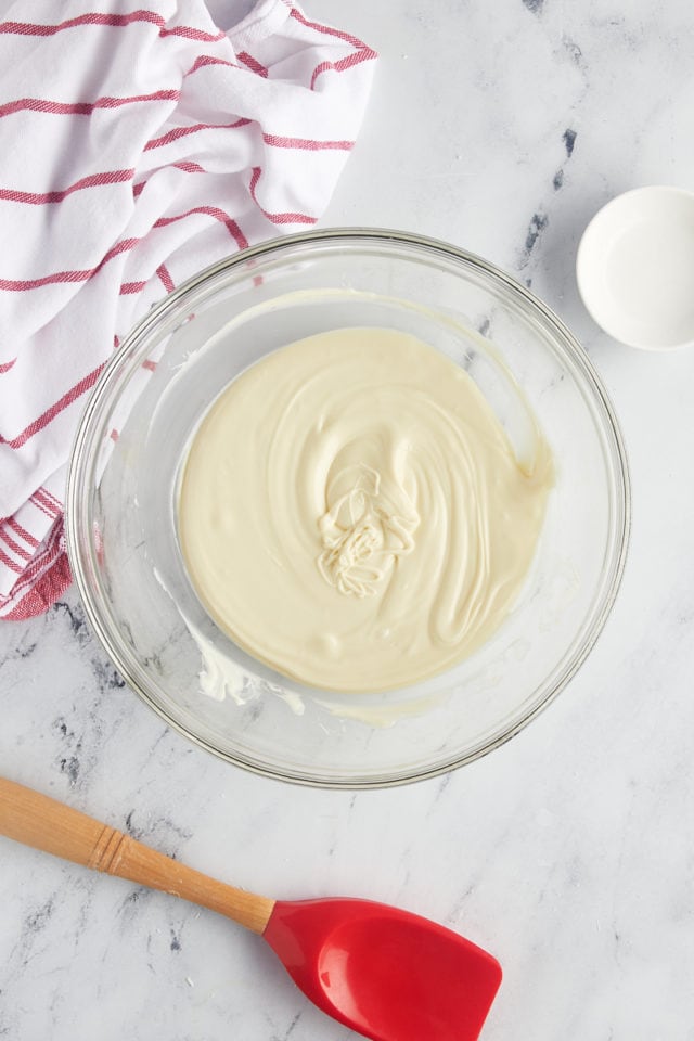 overhead view of melted white chocolate in a glass mixing bowl