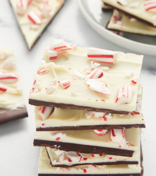 five pieces of peppermint bark stacked together with more bark in the background