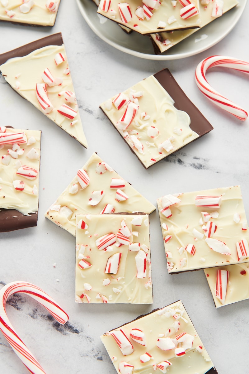 peppermint bark and candy canes scattered on a marble countertop