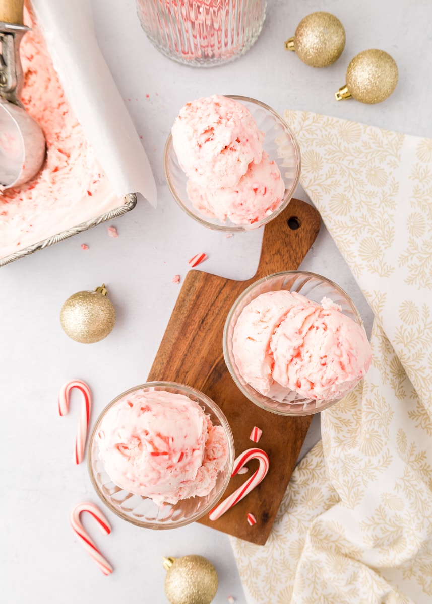 overhead view of three bowls of peppermint ice cream with candy canes and gold ornaments scattered around