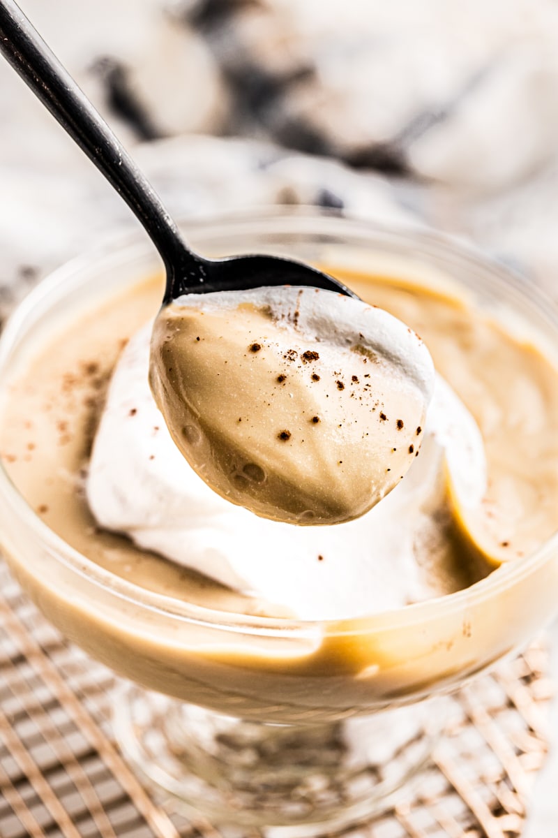 Spoonful of butterscotch pudding held over cup