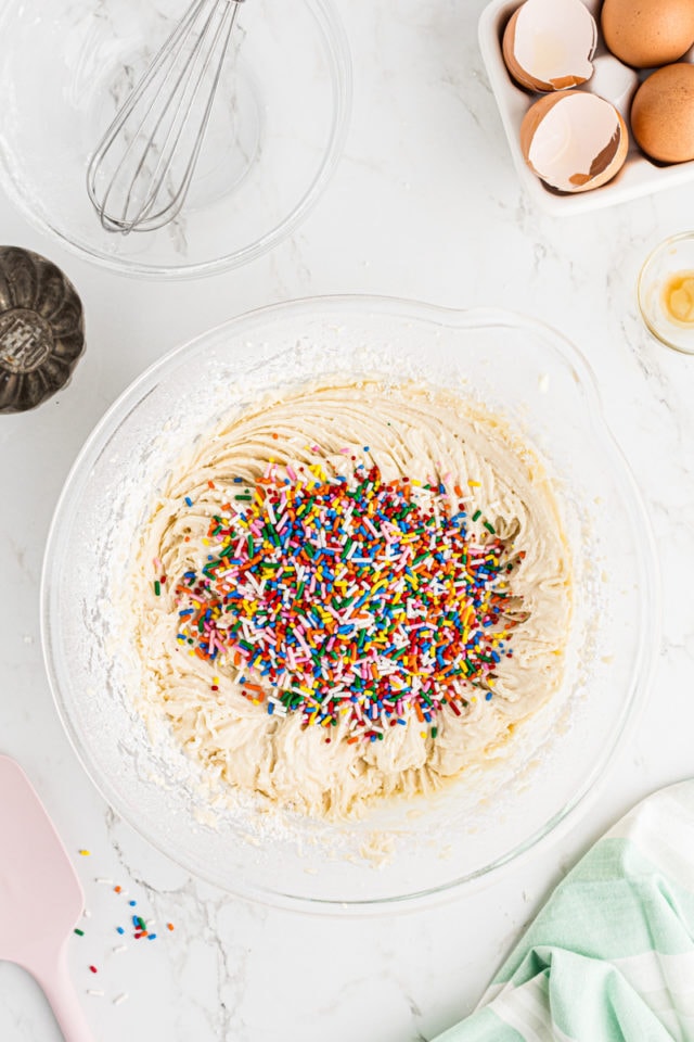 overhead view of sprinkles added to vanilla cupcake batter