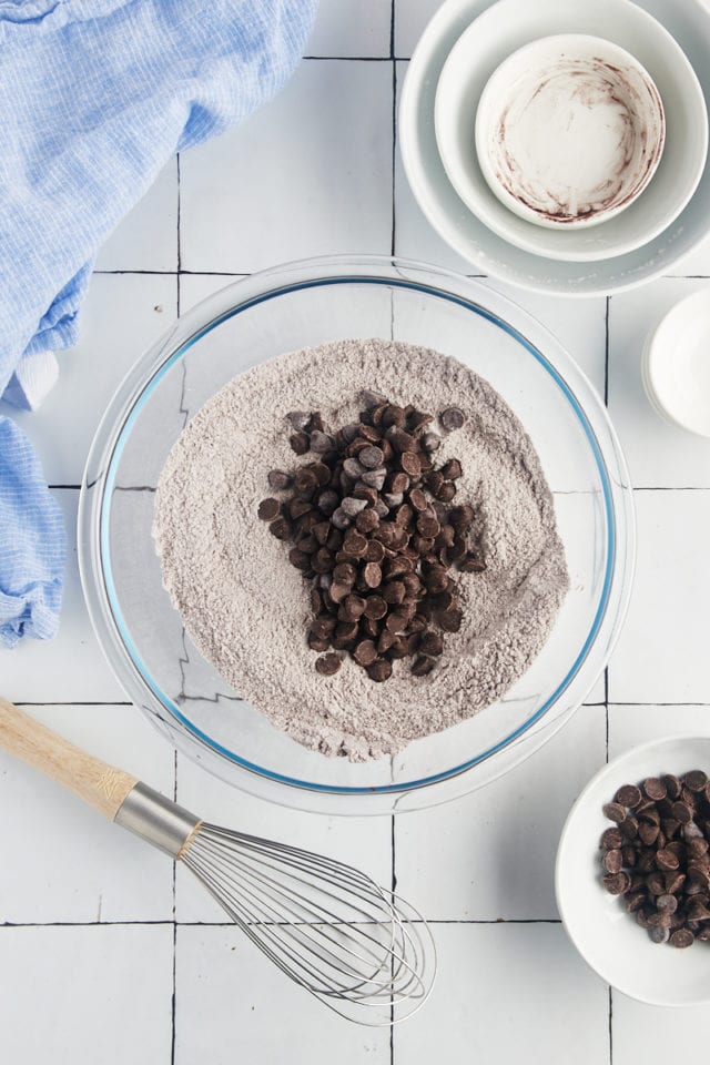 Overhead view of chocolate chips added to bowl of dry ingredients