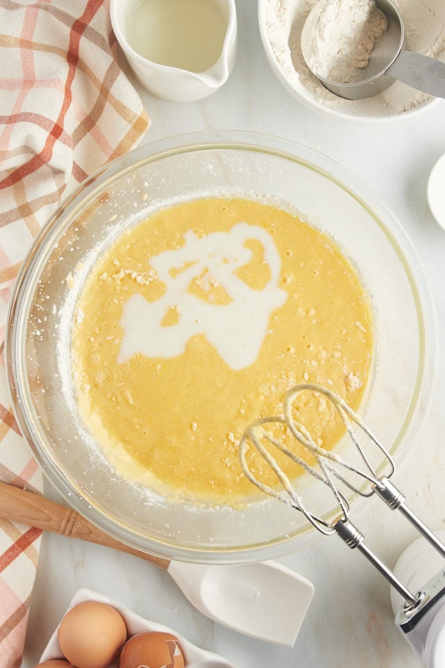 Overhead view of buttermilk added to bowl of cake batter