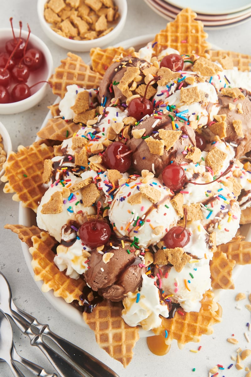 ice cream nachos on a white serving platter with various toppings in bowls around it