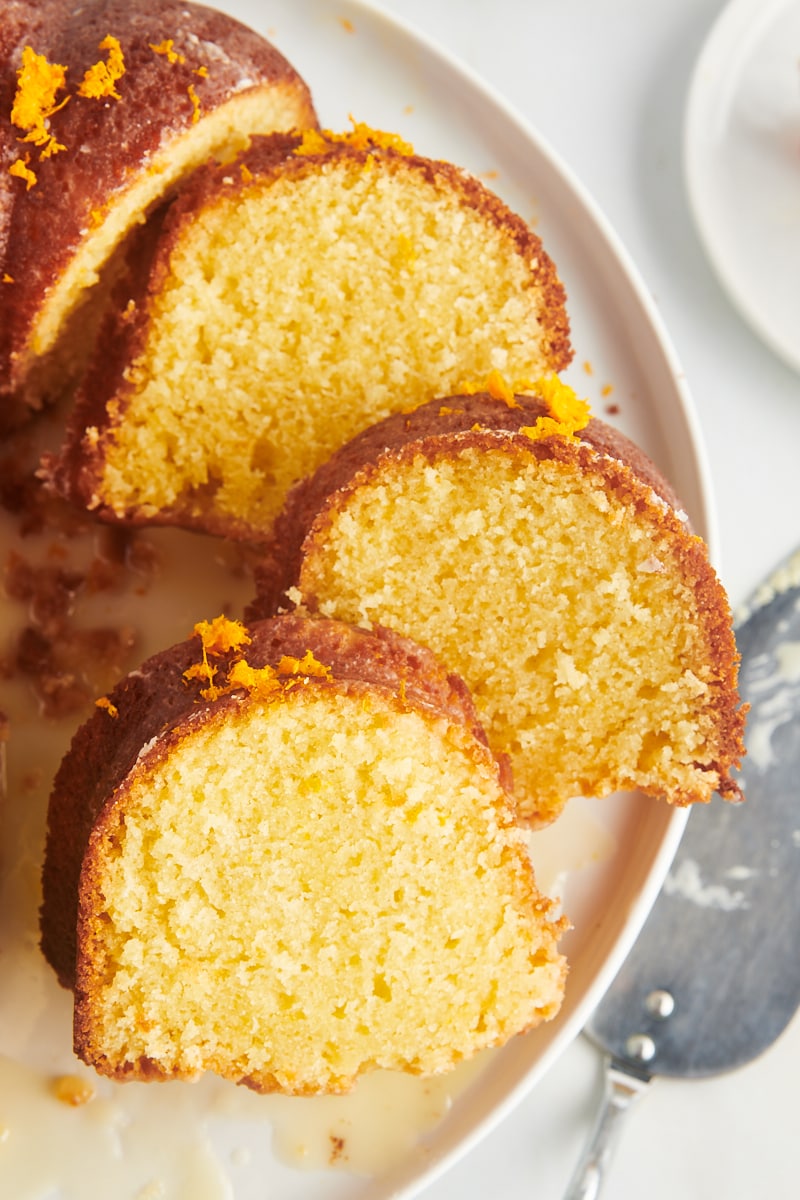 three slices of orange pound cake overlapping each other on a white cake plate