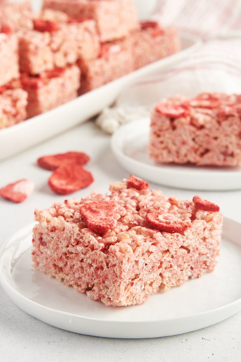 a strawberry rice crispy treat on a white plate with more treats in the background