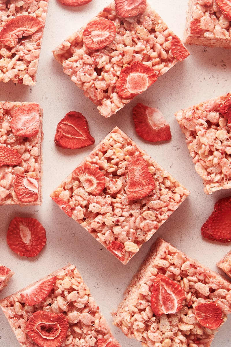 overhead view of strawberry rice crispy treats and freeze-dried strawberries scattered on a white countertop