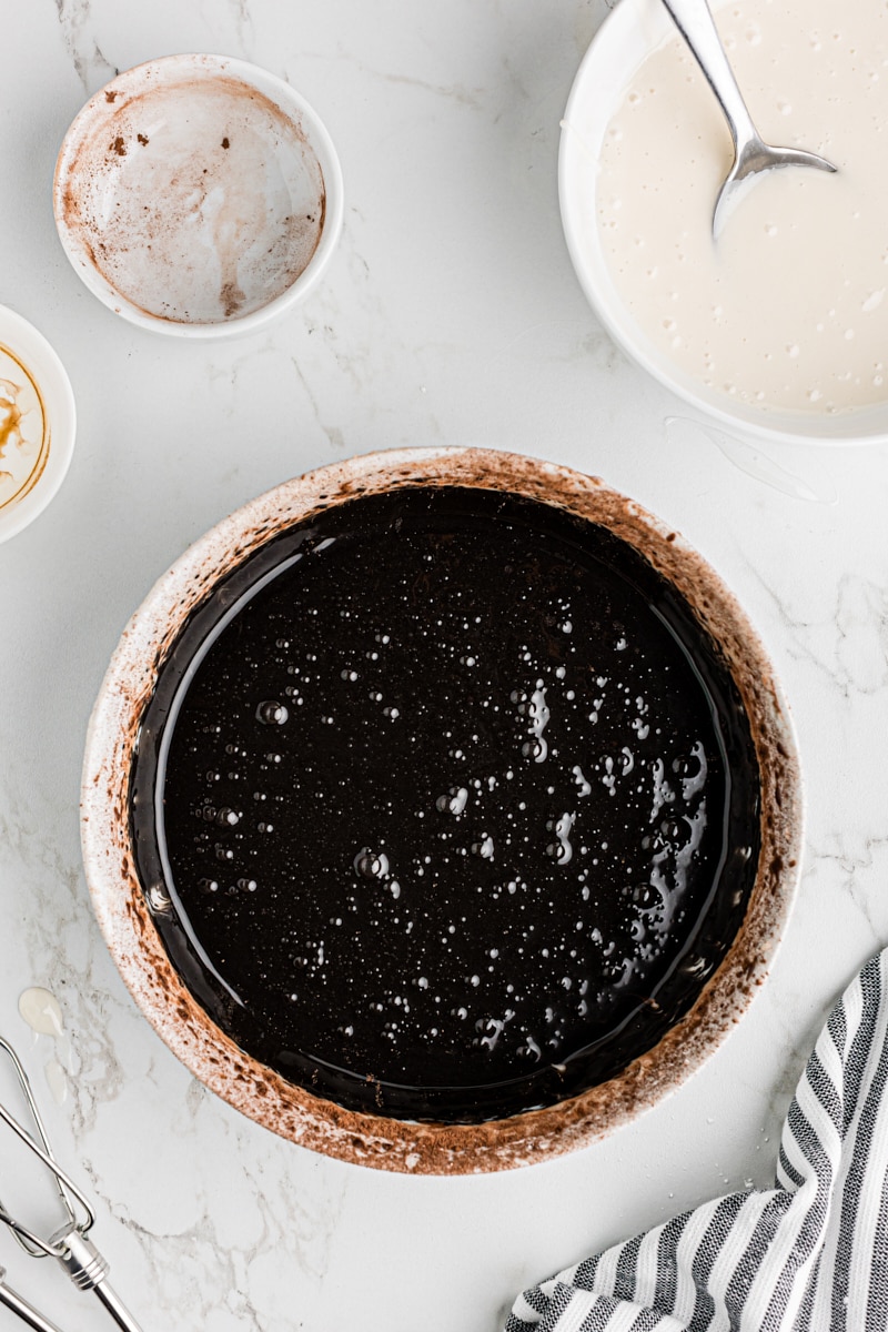 A white bowl holding the rich, dark chocolate icing after mixing.