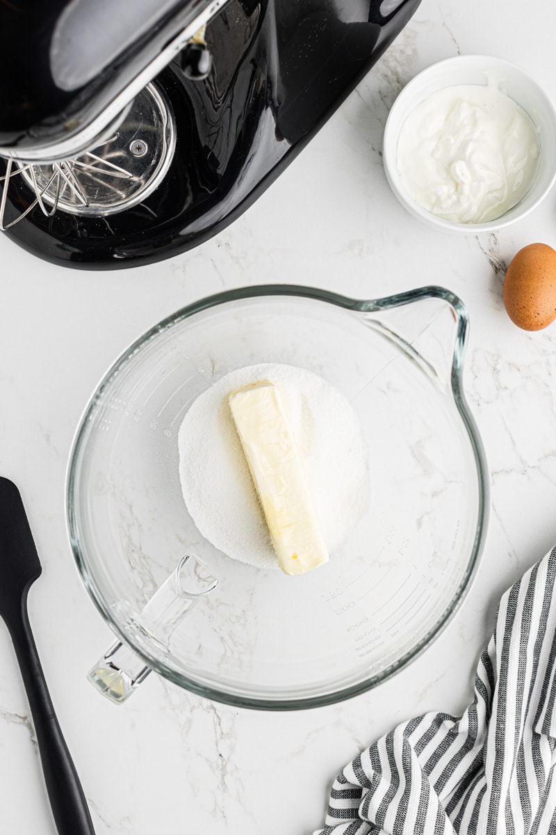 An overhead shot showing softened butter and granulated sugar ready to be creamed in a mixing bowl.