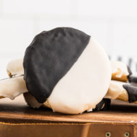 a black and white cookie propped against more cookies on a wooden tray