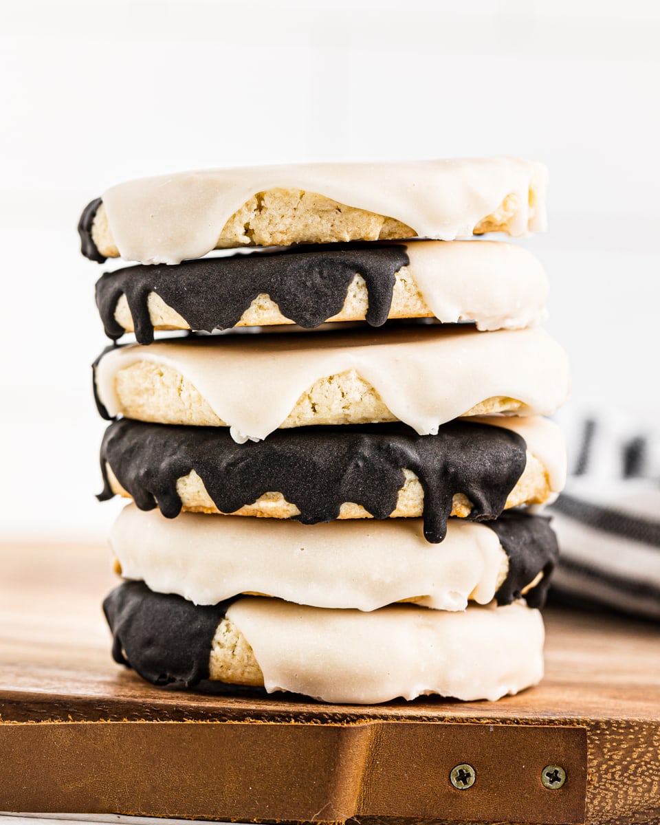 a stack of black and white cookies on a wooden tray