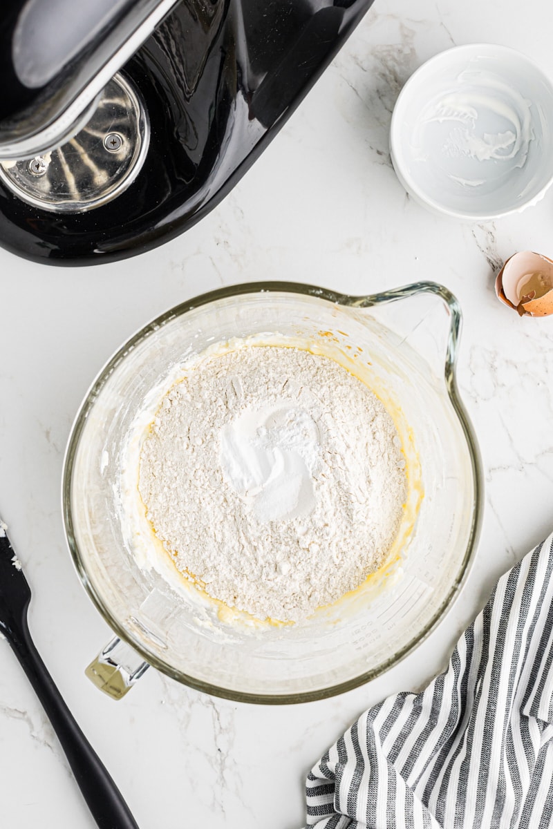 Dry ingredients including flour, baking powder, baking soda, and salt added to the wet mixture in a bowl.