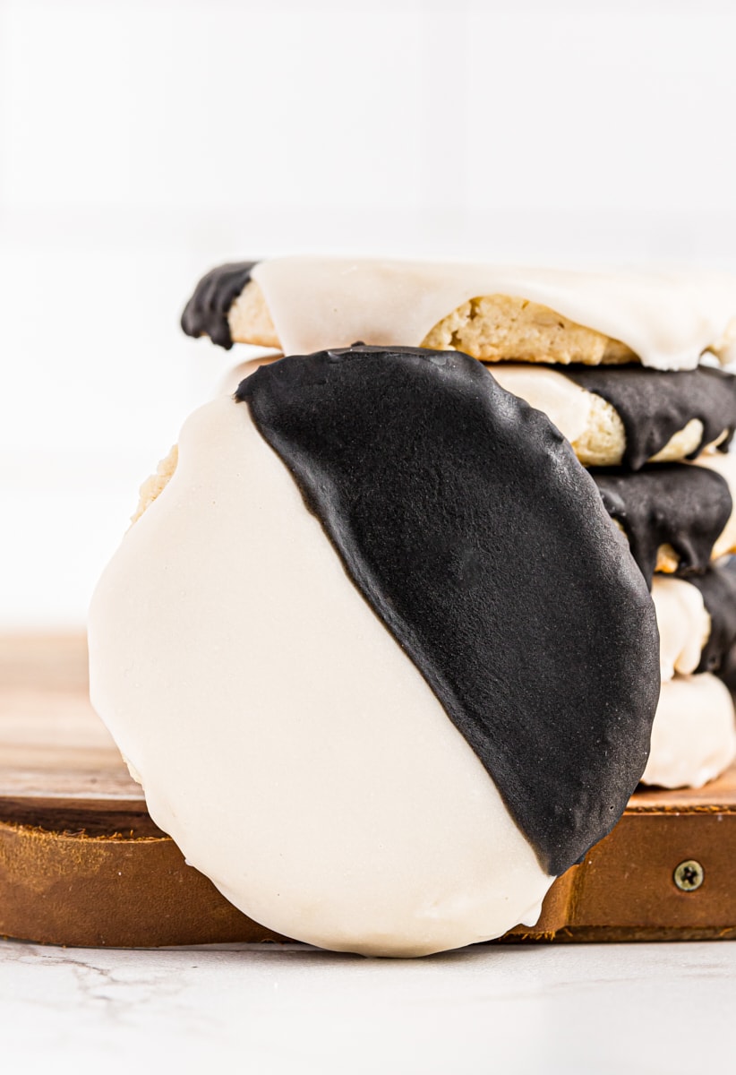 a black and white cookie leaned against a stack of cookies on a wooden board