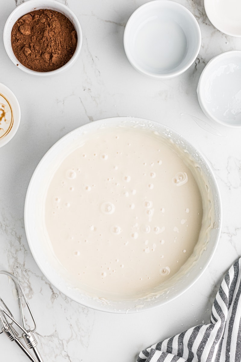 A white bowl filled with freshly mixed, smooth vanilla icing.