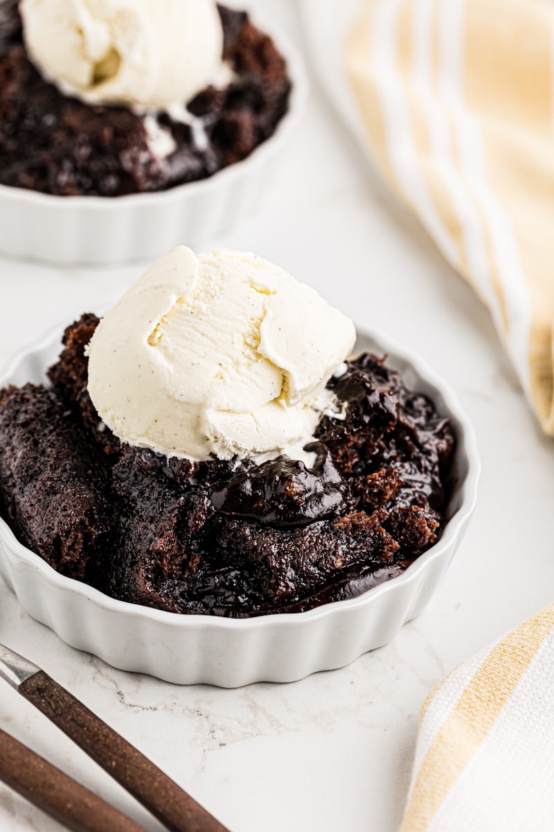 Chocolate cobbler is an easy recipe with amazing results! As it bakes, it forms a cake-like top and a gooey chocolate sauce on the bottom. Chocolate cobbler topped with scoops of vanilla ice cream
