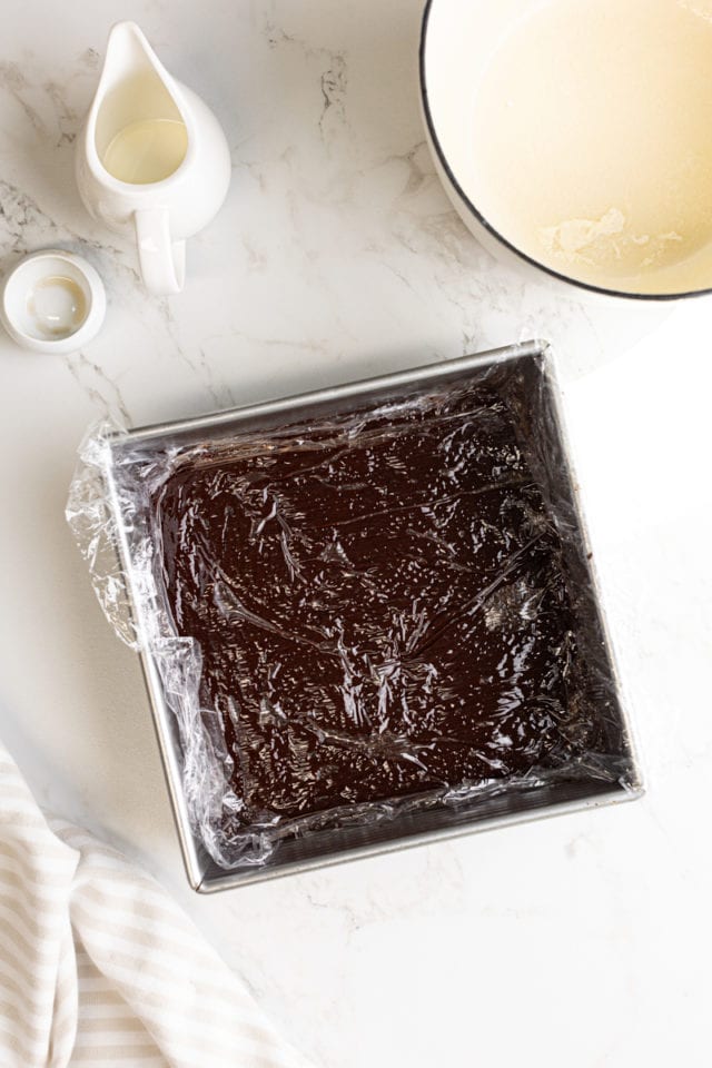 overhead view of chocolate truffle mixture in a square pan covered in plastic wrap