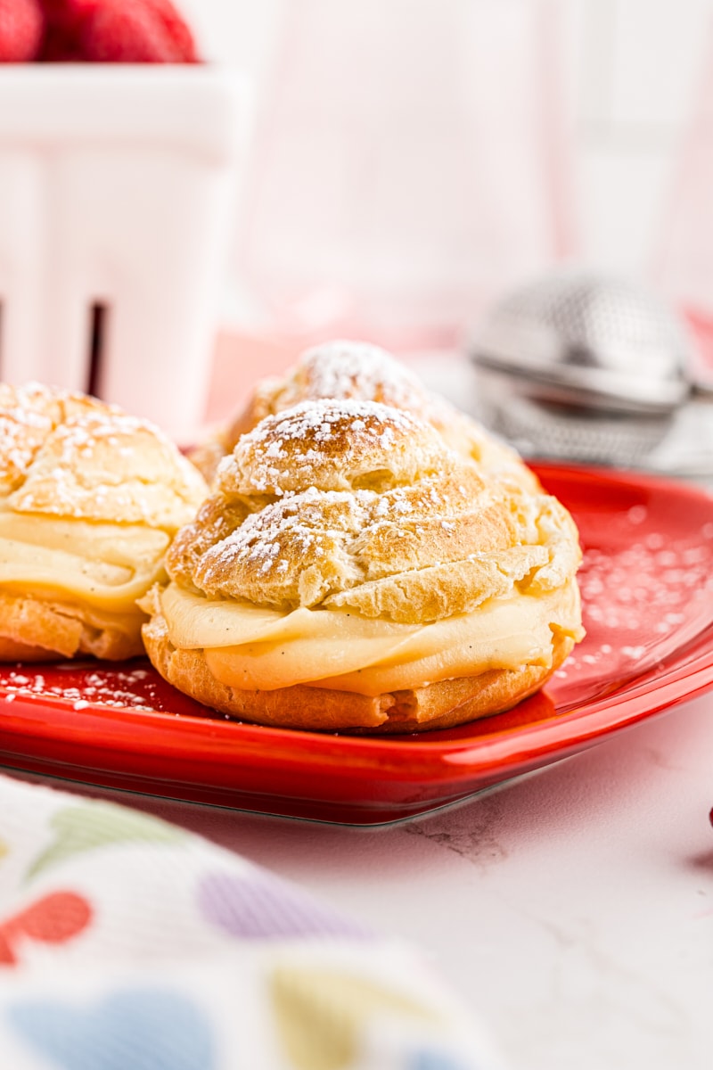 three cream puffs on a red heart-shaped plate