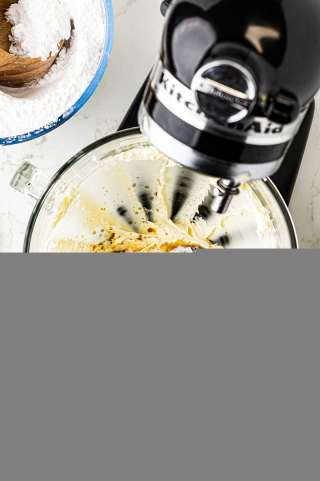 overhead view of vanilla extract, salt, and cream added to creamed butter in the bowl of a stand mixer